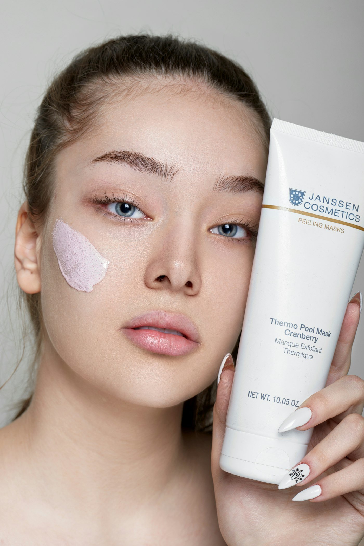 A woman holding a tube of sunscreen next to her face