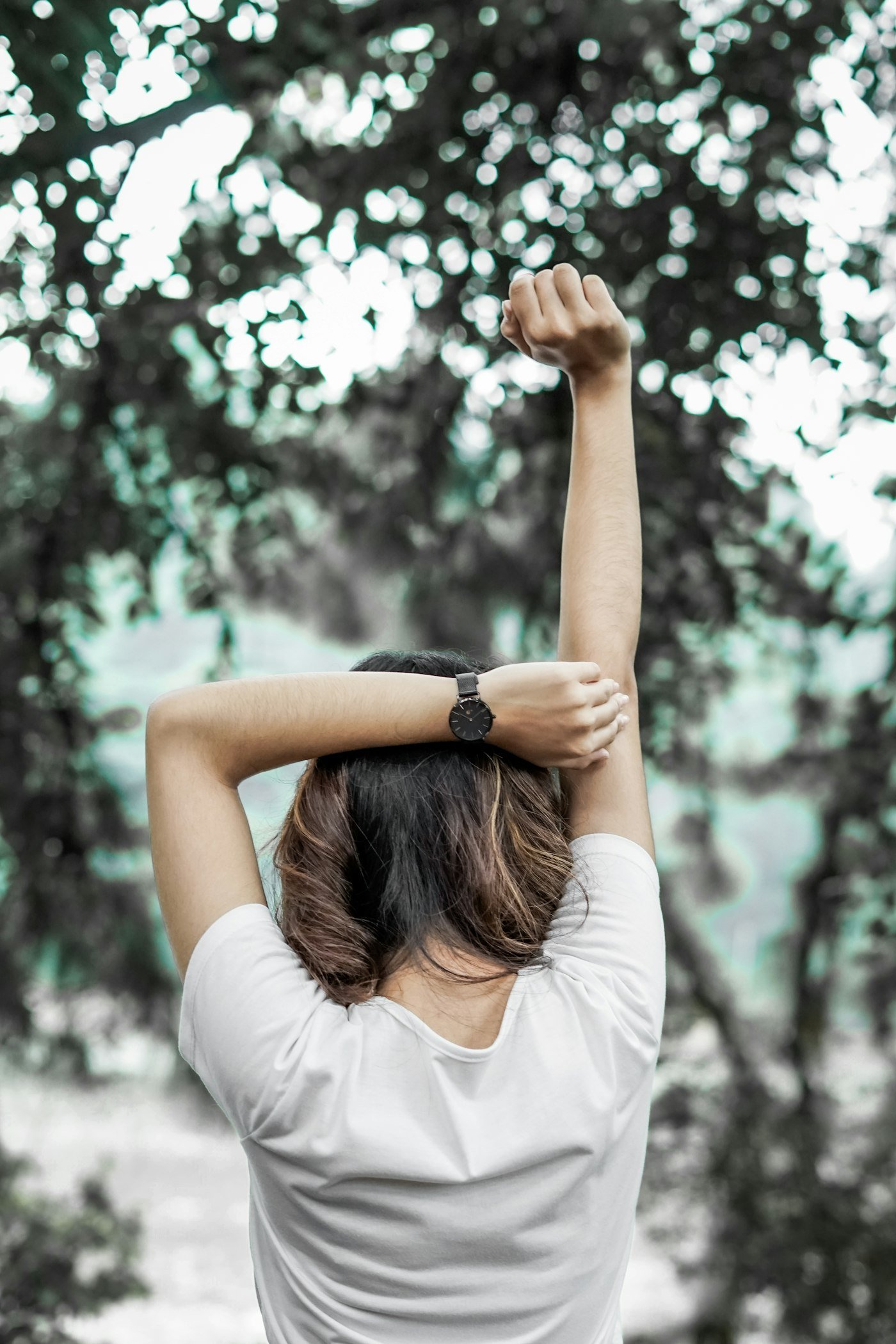 Woman in white long sleeve shirt raising her hands