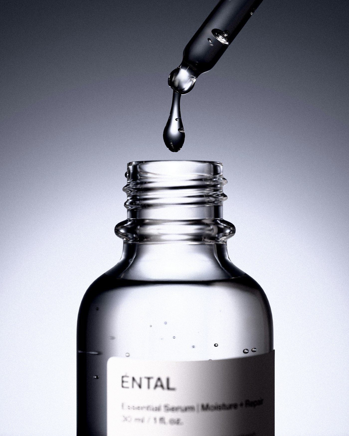 A dropper releases a drop of serum into a bottle