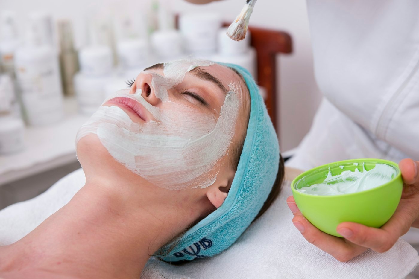 Woman lying on blue towel with white cream on face