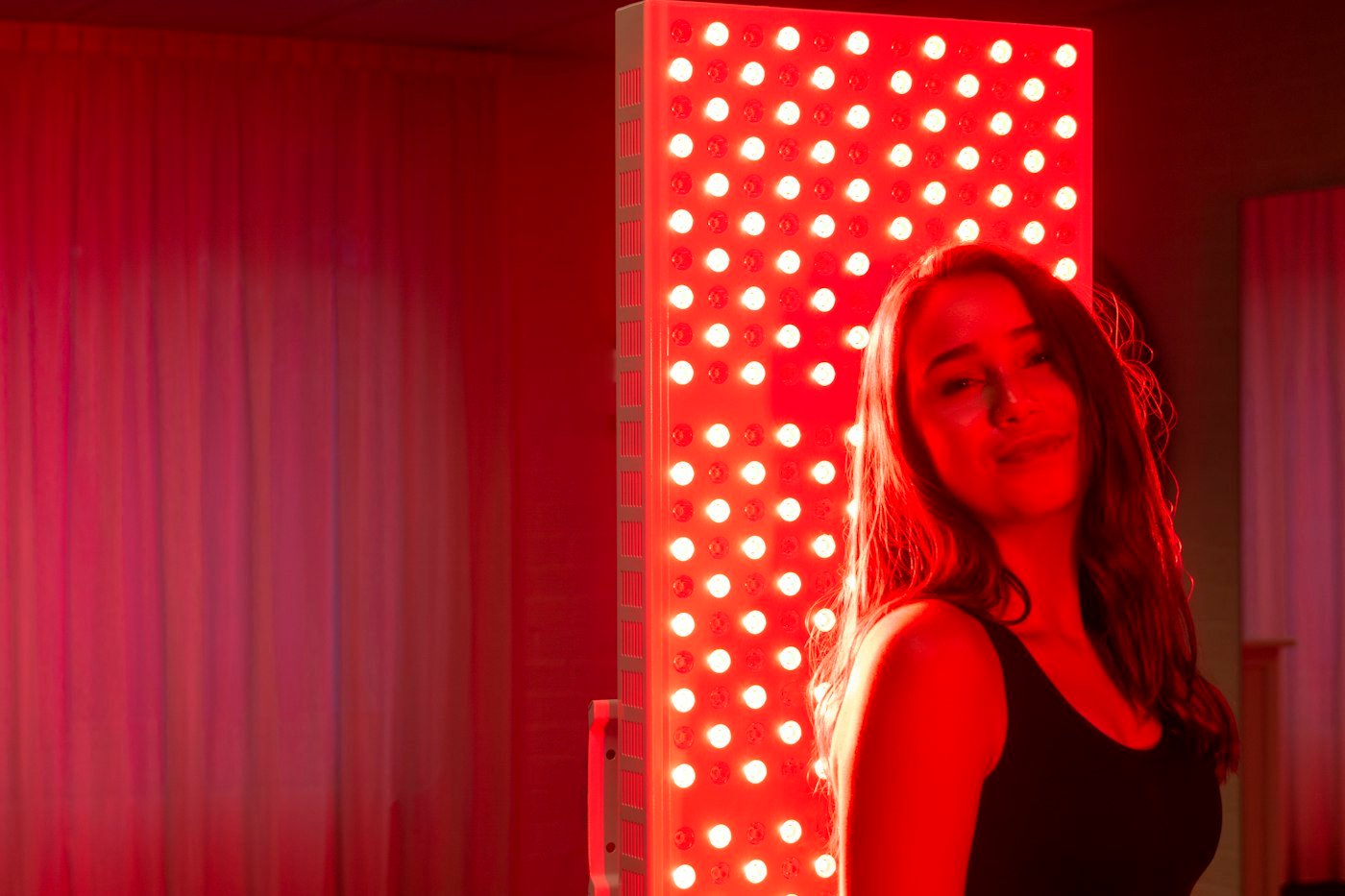 Woman beside a red light therapy panel