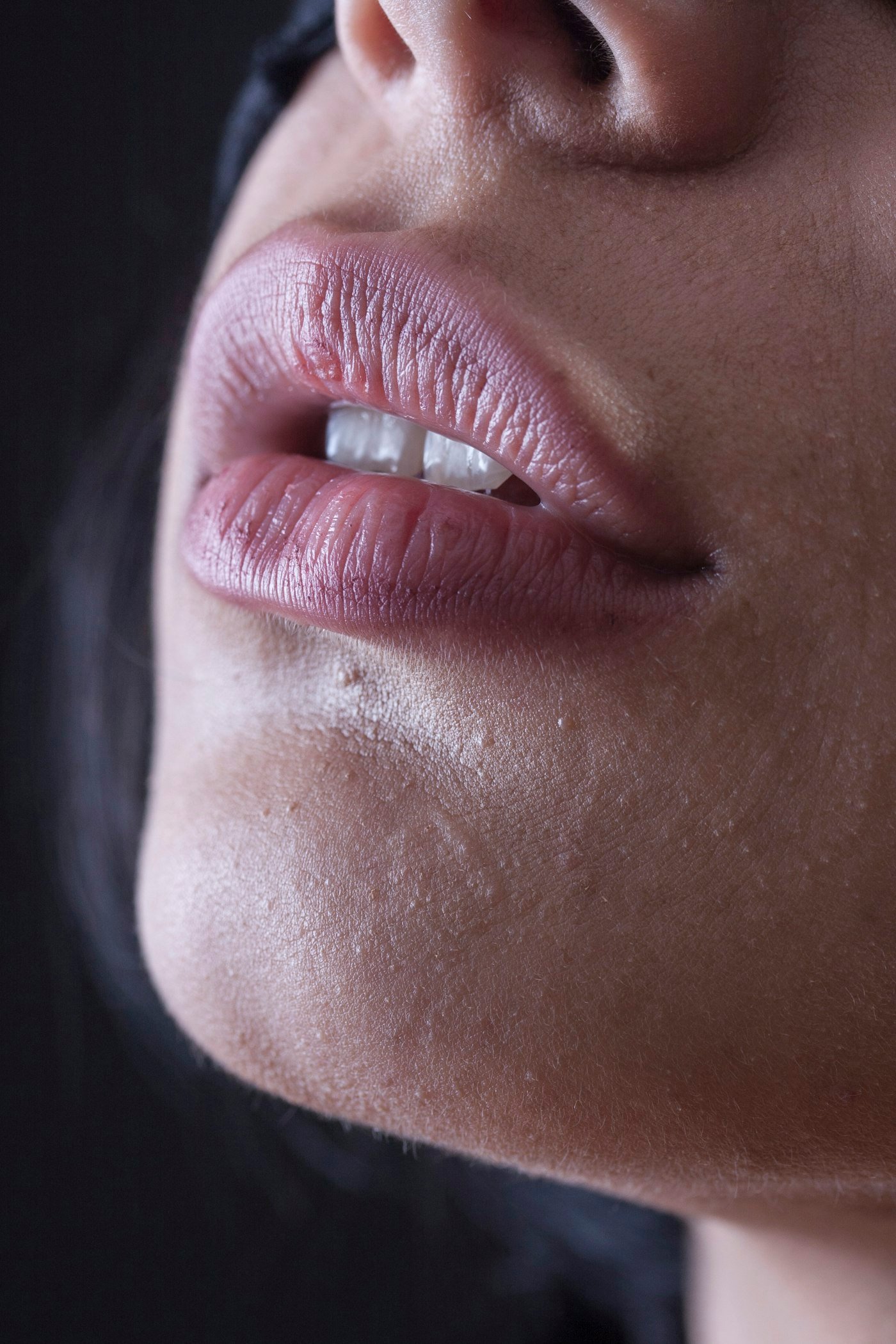 A close-up of a woman's lips slightly parted to reveal white teeth