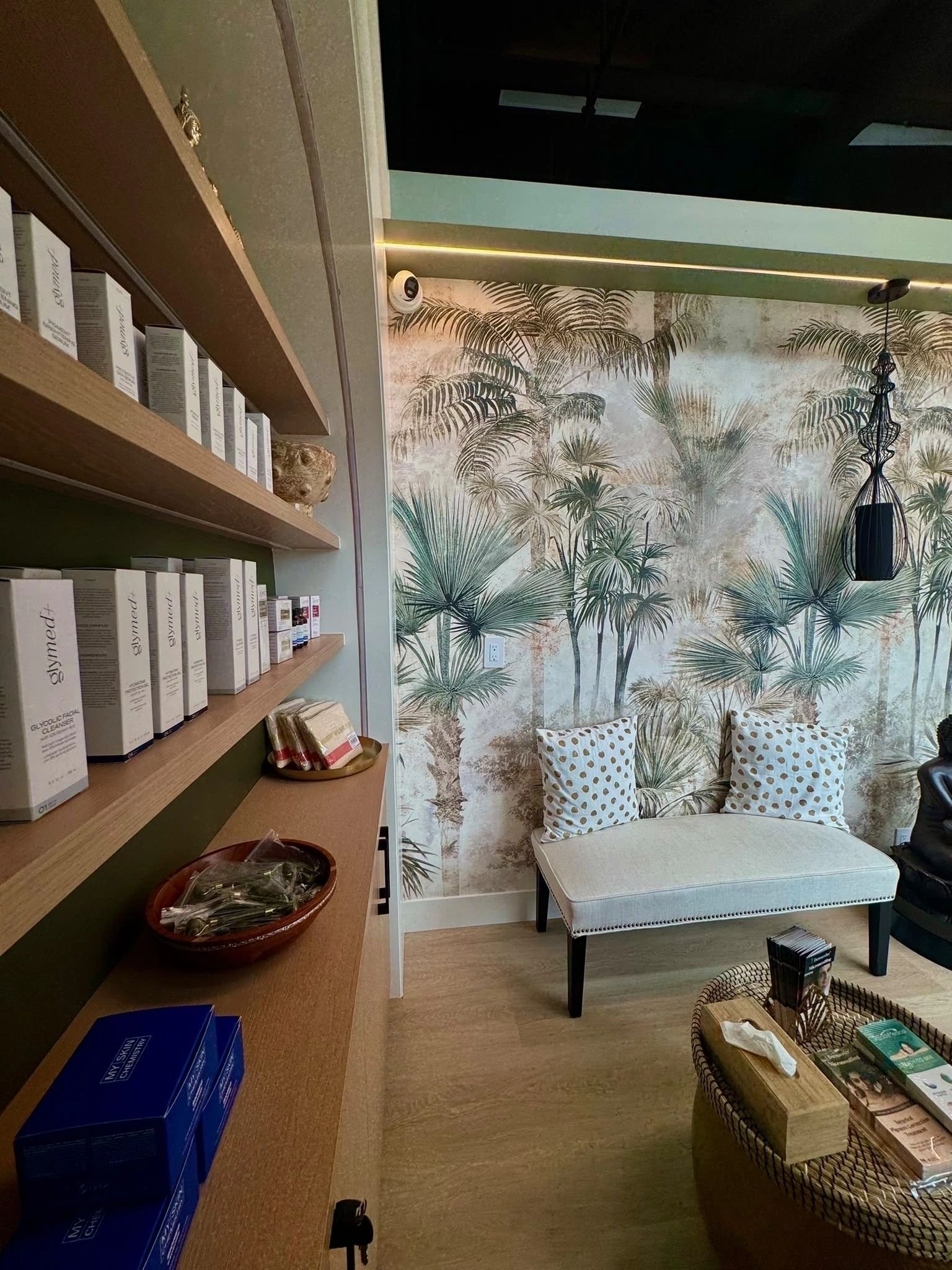 Retail shelves beside the lounge bench and palm wallpaper