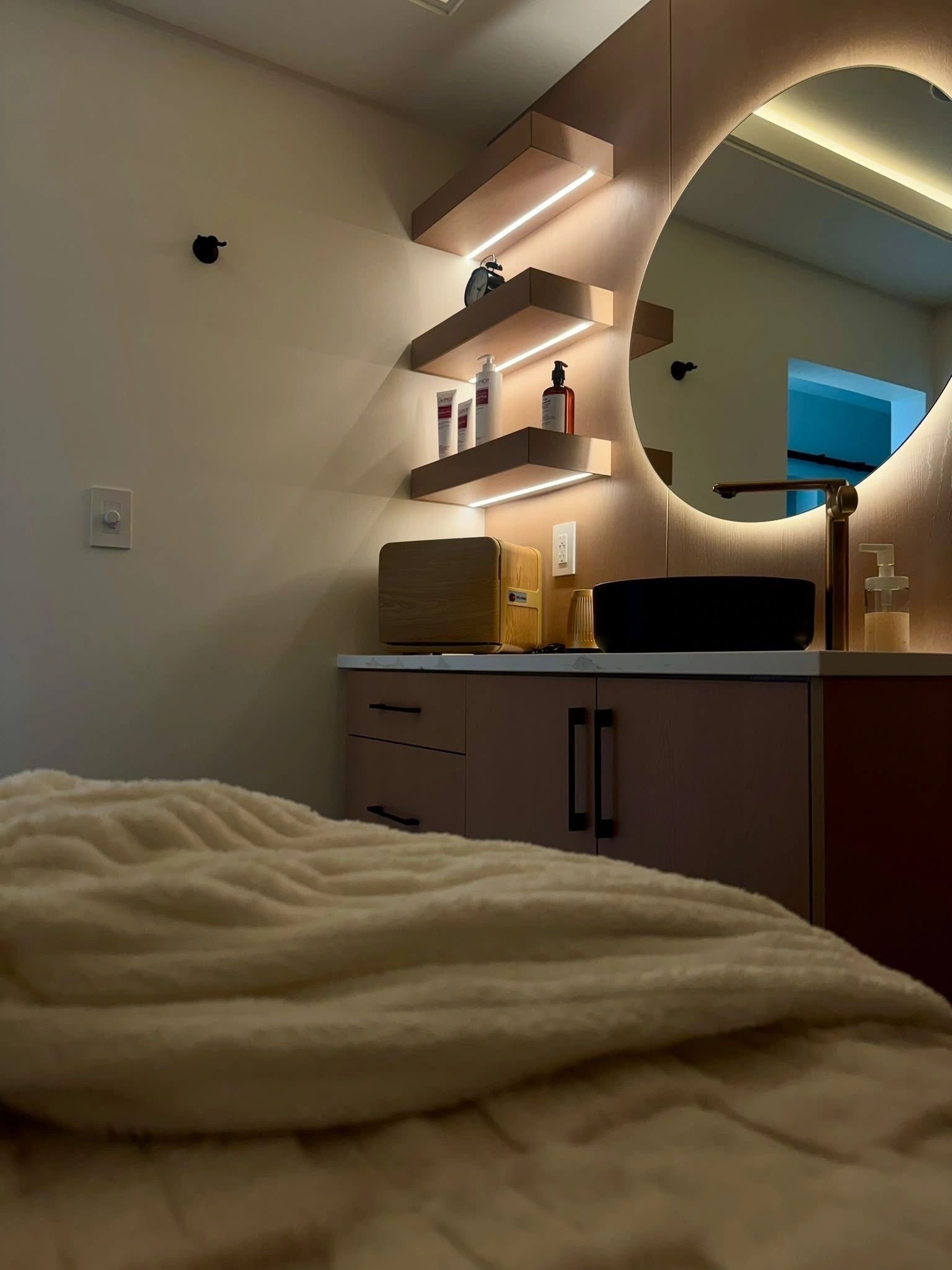 Treatment bed with a soft throw, shelves and mirror lighting