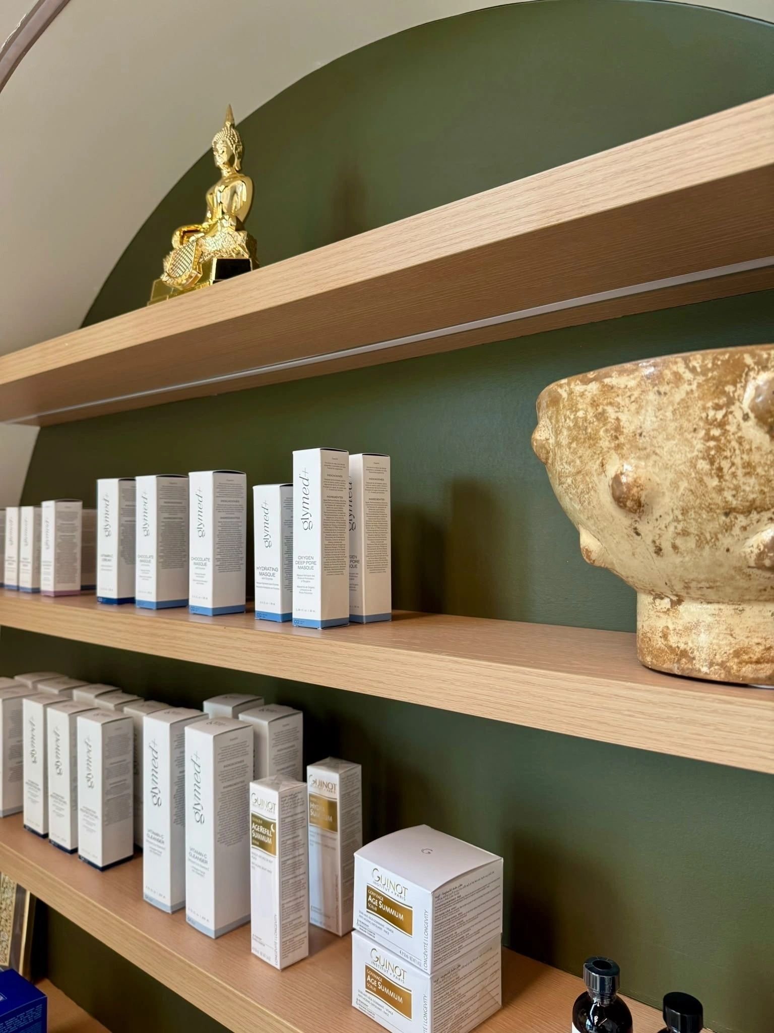 Professional skincare products on wooden shelves against a green wall